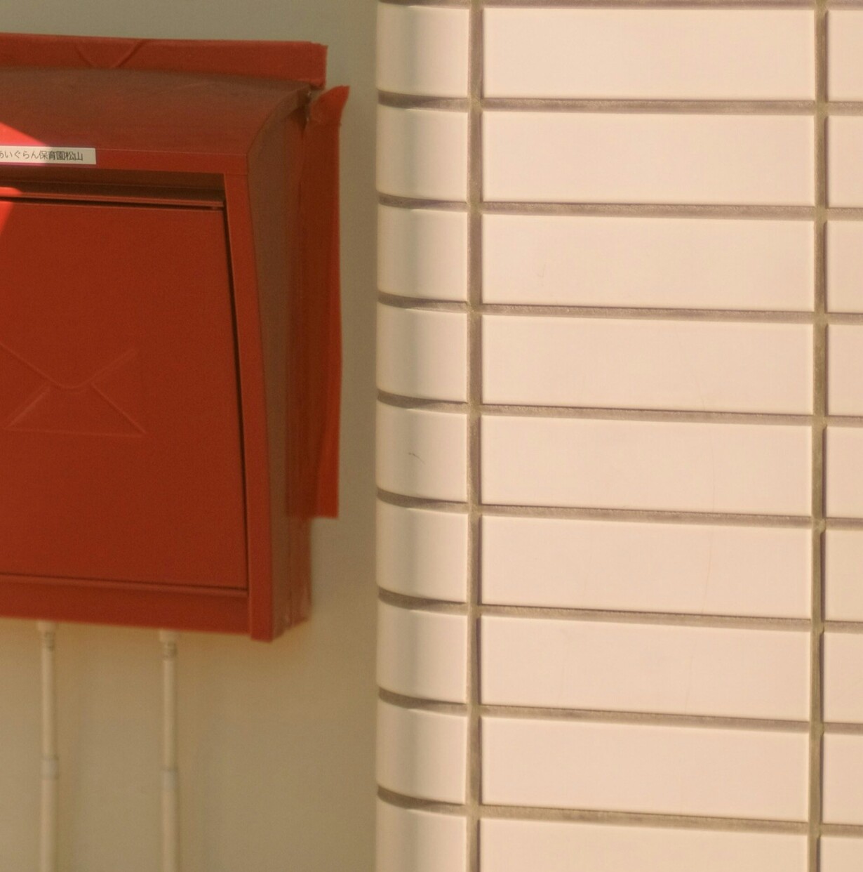 Roter Briefkasten und weiß gefließte Wand.